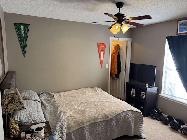 bedroom featuring ceiling fan, a textured ceiling, and carpet flooring