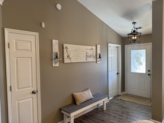 foyer entrance featuring a textured ceiling, an inviting chandelier, lofted ceiling, and hardwood / wood-style flooring