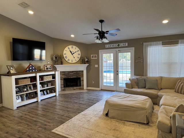 living room with hardwood / wood-style flooring, lofted ceiling, ceiling fan, and a fireplace