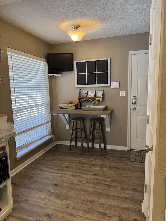 kitchen with dark hardwood / wood-style floors, a kitchen breakfast bar, and a textured ceiling