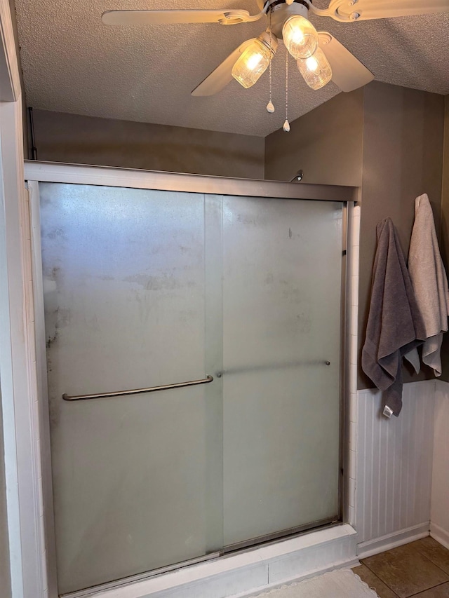 bathroom with a textured ceiling, ceiling fan, tile patterned flooring, and walk in shower