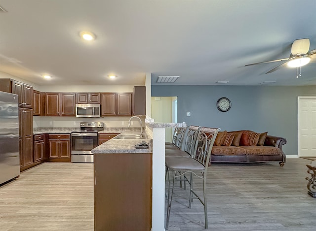4641 Rivers Landing Way, Tallahassee, FL 32303 - kitchen featuring appliances with stainless steel finishes, a breakfast bar area, a peninsula, light wood-style floors, and recessed lighting