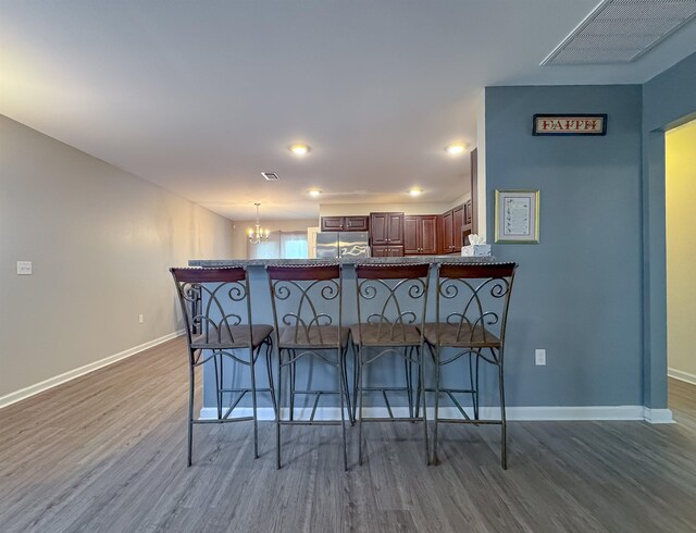 4641 Rivers Landing Way, Tallahassee, FL 32303 - kitchen featuring stainless steel refrigerator, a kitchen bar, wood finished floors, a peninsula, and a chandelier