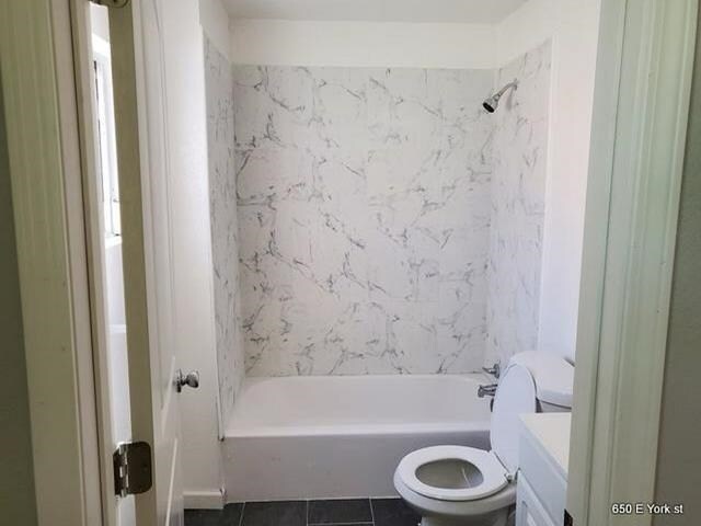 full bathroom with tiled shower / bath combo, vanity, tile patterned floors, and toilet