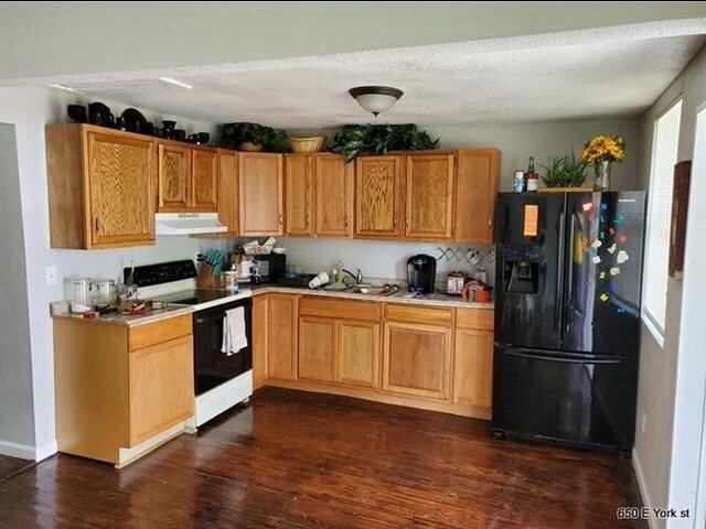 kitchen featuring black refrigerator with ice dispenser, white range oven, sink, and dark wood-type flooring