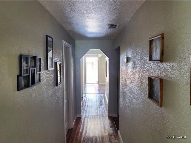 hallway with a textured ceiling and hardwood / wood-style flooring