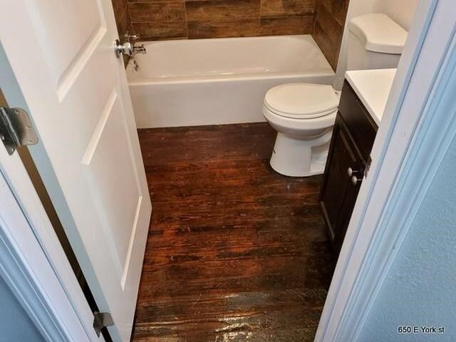 bathroom featuring hardwood / wood-style floors, vanity, a tub to relax in, and toilet