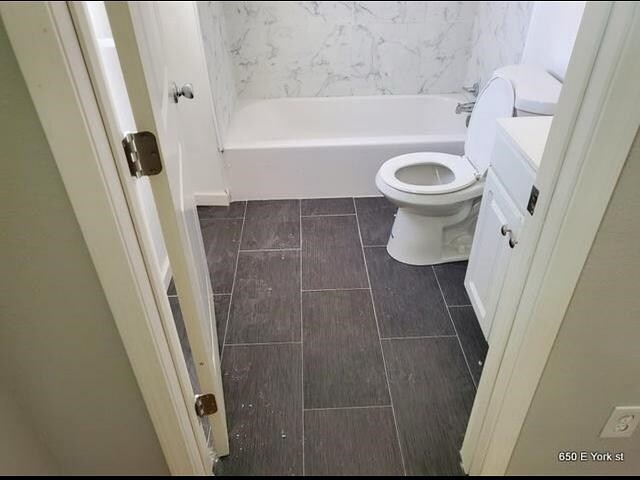 bathroom featuring toilet, a tub to relax in, and vanity