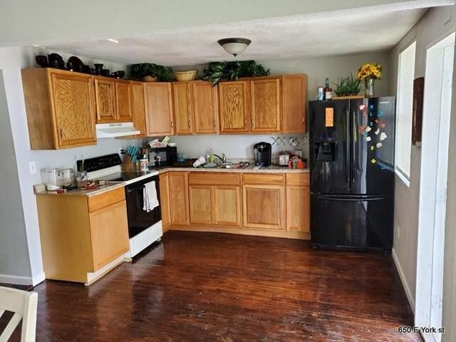 kitchen featuring dark hardwood / wood-style flooring, black refrigerator with ice dispenser, white range oven, and sink