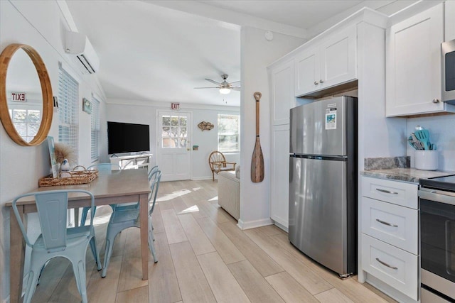 kitchen featuring stainless steel appliances, white cabinets, an AC wall unit, ceiling fan, and light hardwood / wood-style floors