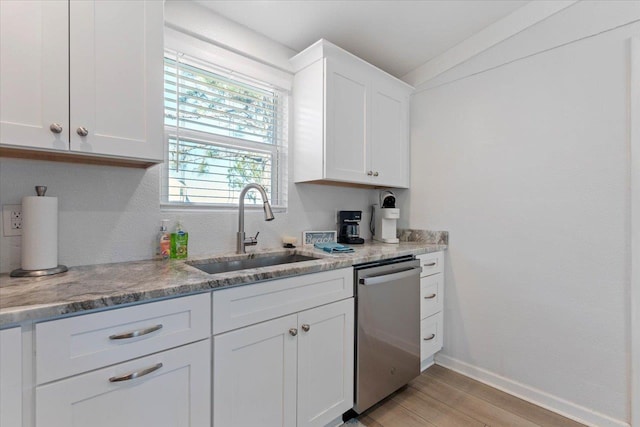 kitchen with stainless steel dishwasher, white cabinetry, light hardwood / wood-style floors, and sink