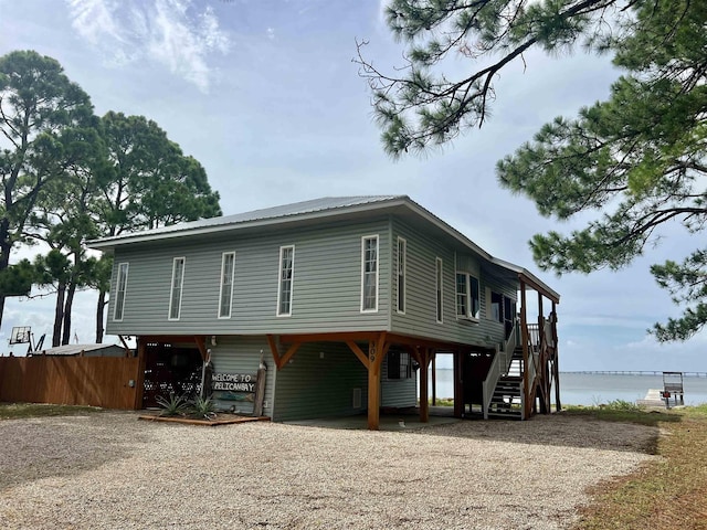 view of front of house with a water view, fence, and stairway