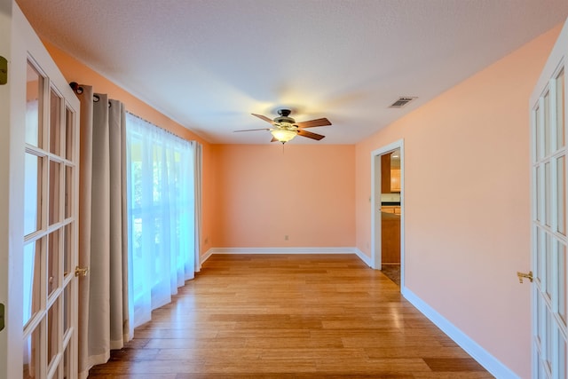 spare room with ceiling fan, a textured ceiling, and light wood-type flooring