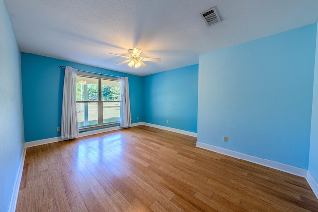 empty room featuring ceiling fan, a textured ceiling, and light wood-type flooring