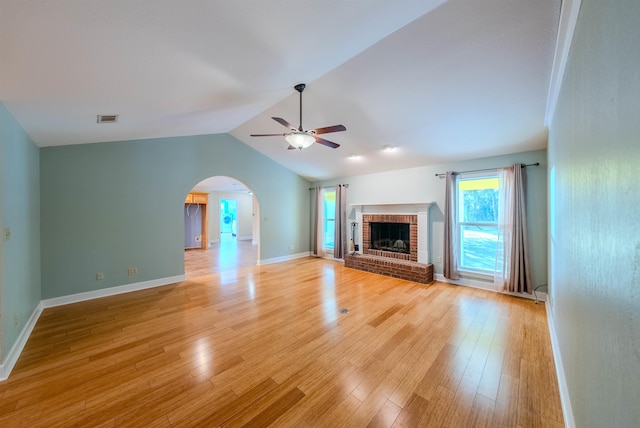 unfurnished living room featuring a brick fireplace, light wood-type flooring, vaulted ceiling, and ceiling fan