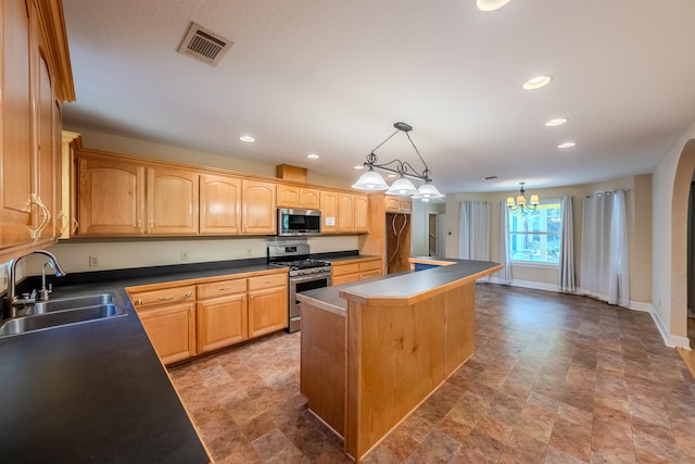 kitchen featuring appliances with stainless steel finishes, sink, decorative light fixtures, a chandelier, and a center island