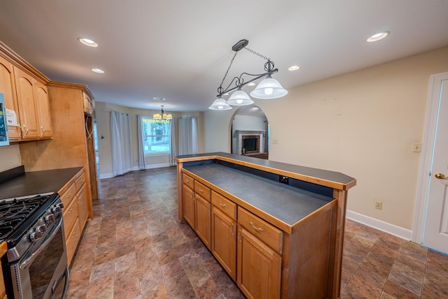 kitchen with a notable chandelier, decorative light fixtures, stainless steel gas range oven, and a kitchen island