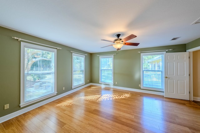 empty room with plenty of natural light, ceiling fan, and light hardwood / wood-style flooring