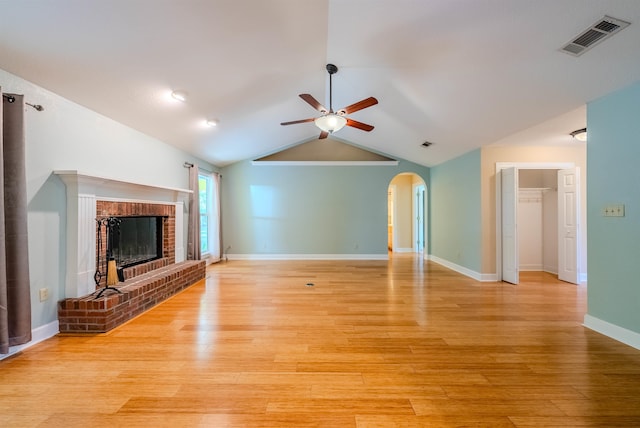 unfurnished living room featuring a brick fireplace, ceiling fan, light wood-type flooring, and vaulted ceiling