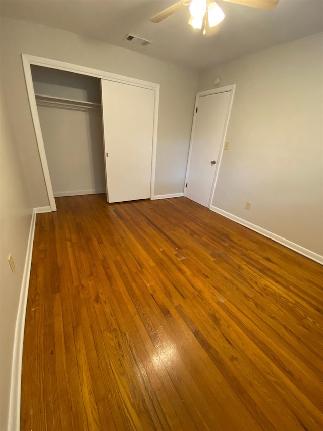 unfurnished bedroom with ceiling fan, a closet, and wood-type flooring