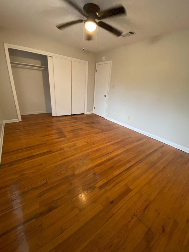 unfurnished bedroom featuring hardwood / wood-style flooring, ceiling fan, and a closet