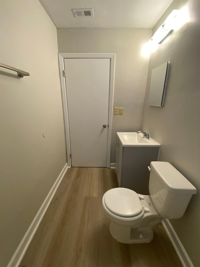 bathroom with hardwood / wood-style floors, vanity, and toilet