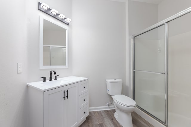 bathroom with toilet, vanity, hardwood / wood-style floors, and a shower with shower door