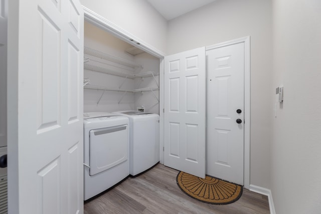 washroom with washing machine and clothes dryer and light hardwood / wood-style flooring