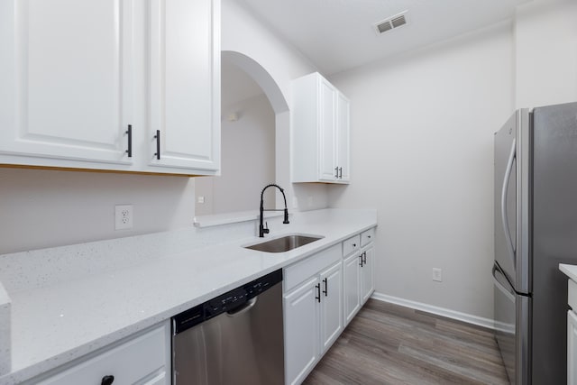 kitchen featuring stainless steel appliances, hardwood / wood-style flooring, sink, light stone countertops, and white cabinets