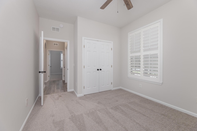 unfurnished bedroom with a closet, light carpet, and ceiling fan