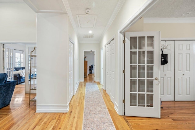 corridor featuring crown molding, light hardwood / wood-style floors, and french doors