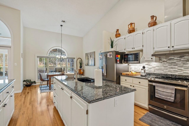 kitchen featuring sink, white cabinetry, decorative light fixtures, stainless steel appliances, and a kitchen island with sink