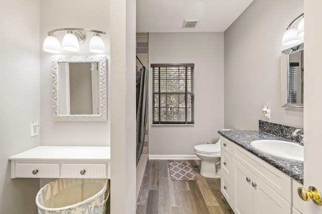 bathroom with toilet, wood-type flooring, a textured ceiling, vanity, and curtained shower