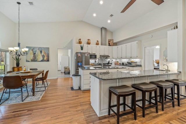 kitchen featuring sink, white cabinets, a kitchen bar, kitchen peninsula, and stainless steel appliances