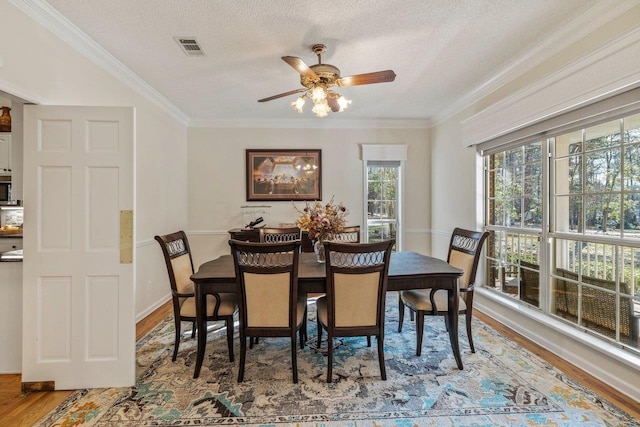 dining space with hardwood / wood-style flooring, ceiling fan, ornamental molding, and a textured ceiling