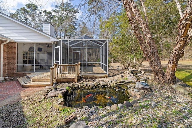 view of yard with ceiling fan, a deck, and glass enclosure