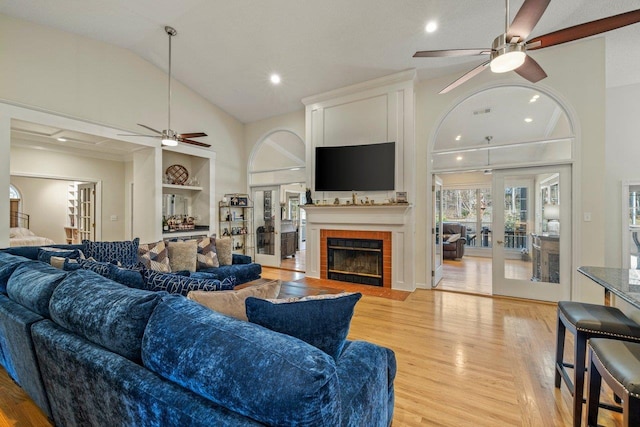 living room with light hardwood / wood-style flooring, built in features, ceiling fan, a fireplace, and french doors