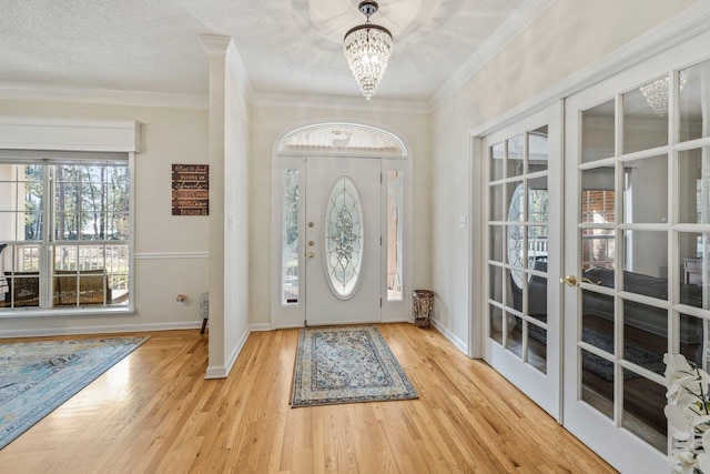 entrance foyer with ornamental molding, light wood-type flooring, and a textured ceiling