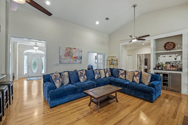 living room featuring high vaulted ceiling, indoor bar, wine cooler, ceiling fan, and light hardwood / wood-style floors