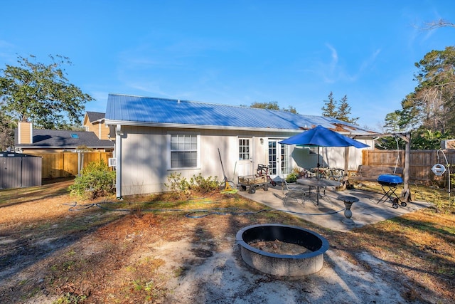 rear view of property with a patio and an outdoor fire pit