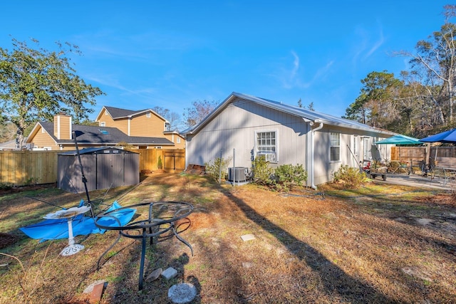 rear view of property featuring a shed, central air condition unit, and a patio area