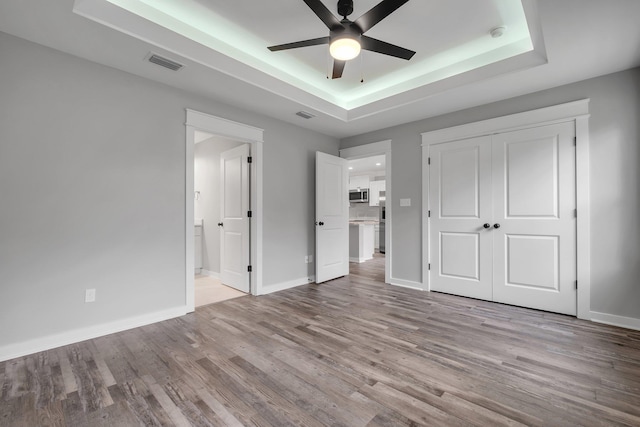 1695 Landing St, Carrabelle, FL 32322 - unfurnished bedroom with a raised ceiling, wood finished floors, a closet, ensuite bath, and ceiling fan