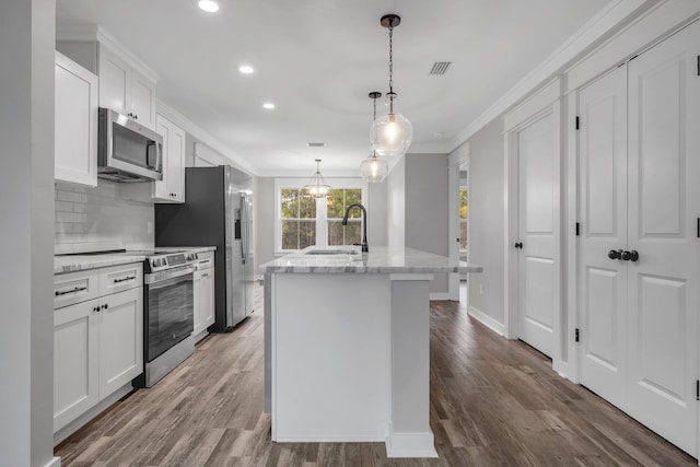 1695 Landing St, Carrabelle, FL 32322 - kitchen featuring stainless steel appliances, recessed lighting, ornamental molding, an island with sink, and white cabinetry