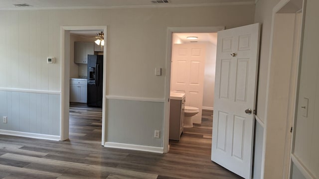 hall with dark hardwood / wood-style flooring, wooden walls, and ornamental molding