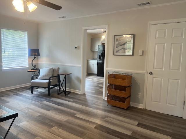 sitting room featuring ceiling fan, crown molding, and dark wood-type flooring