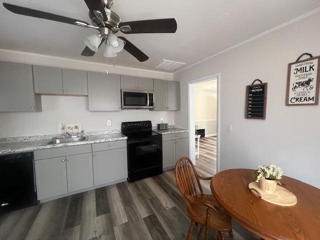 kitchen with crown molding, sink, dark wood-type flooring, black appliances, and gray cabinets