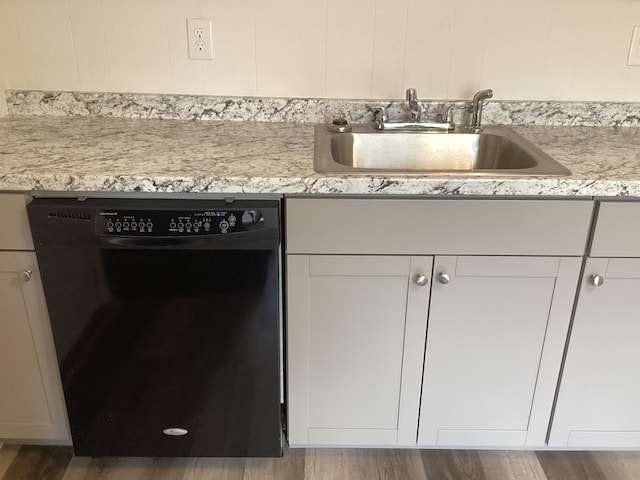 kitchen featuring sink, light stone countertops, black dishwasher, and dark wood-type flooring