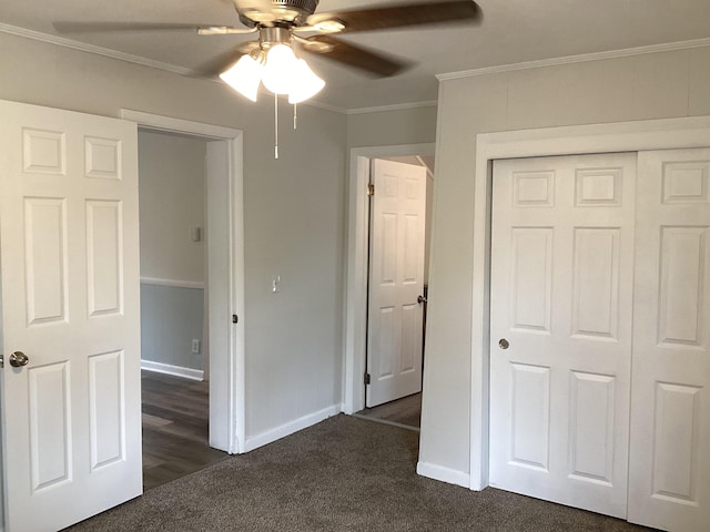 unfurnished bedroom with a closet, dark carpet, ceiling fan, and crown molding