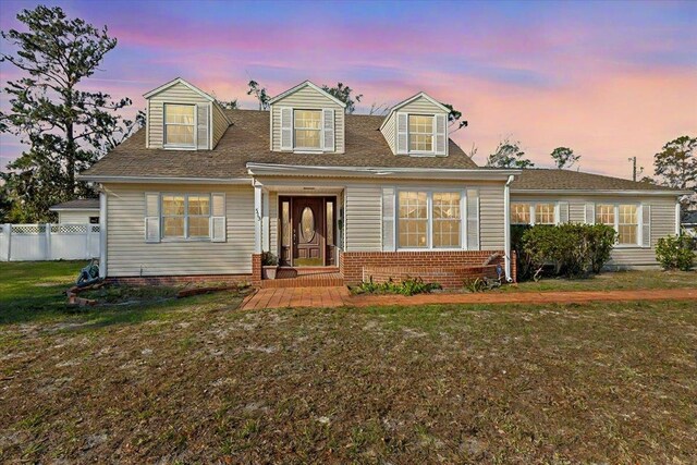 cape cod house featuring a yard