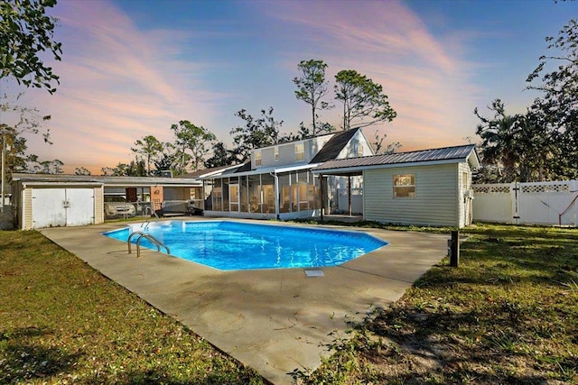 pool at dusk featuring a shed, a lawn, and a sunroom